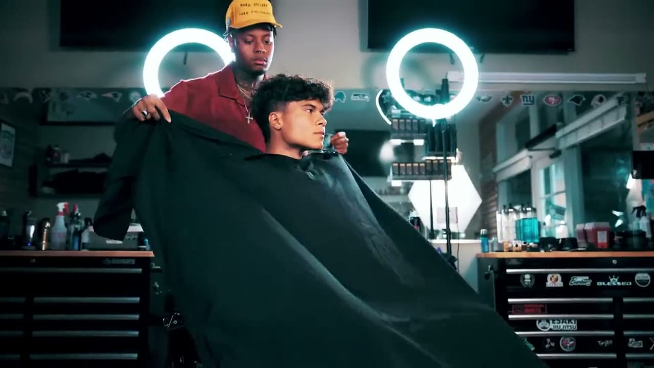 A barber preparing a client in a studio chair